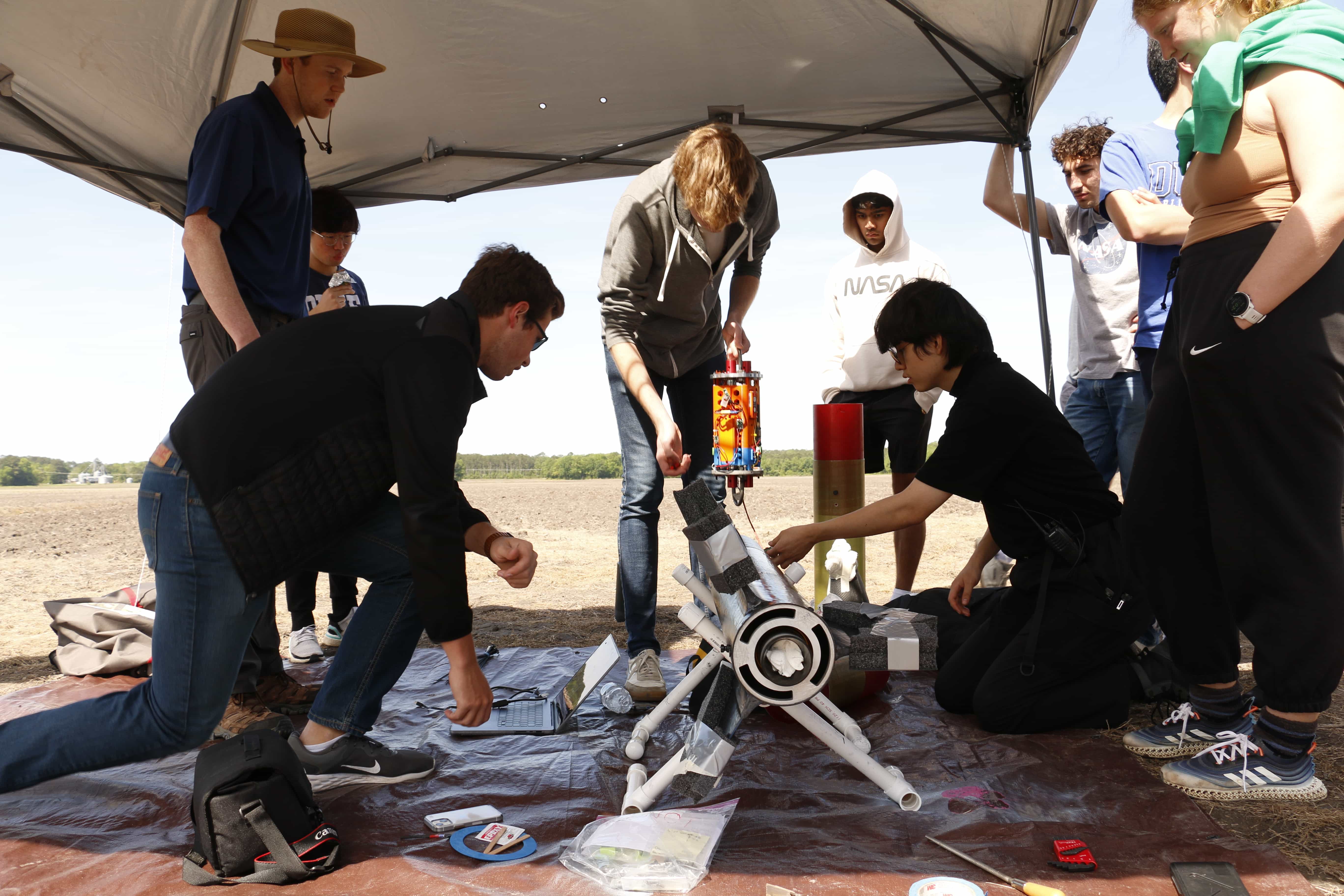 group working on the rocket under a tent