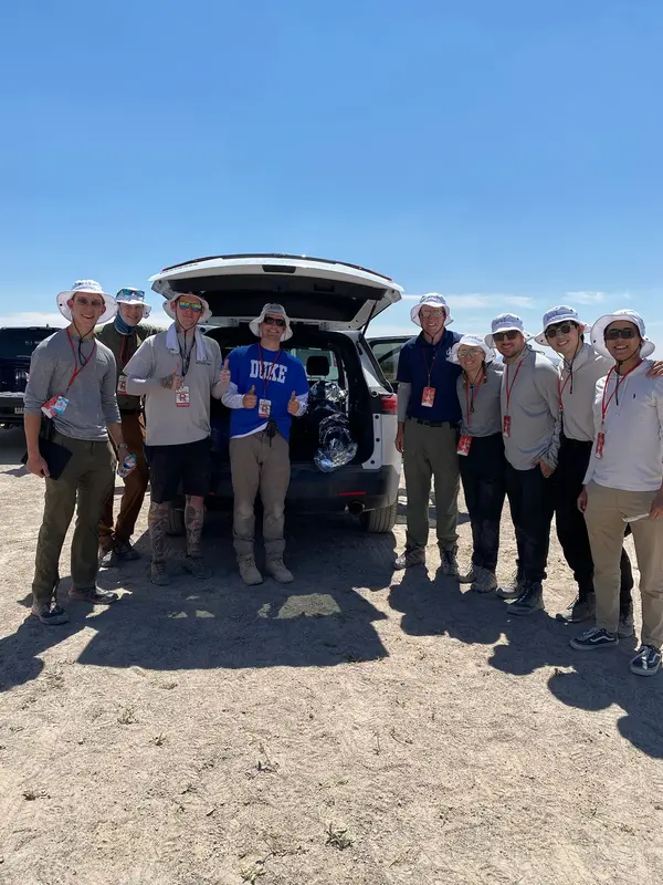 Team standing next to the rocket in the back of a car.